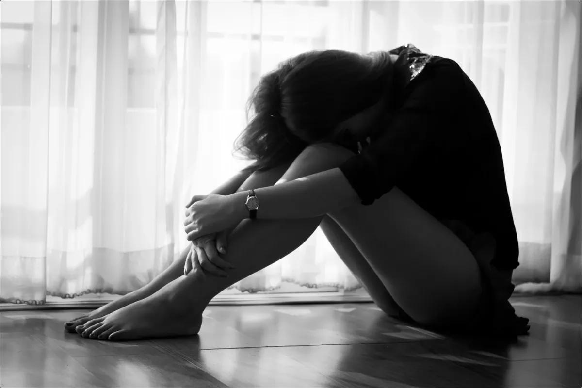 woman sitting on the floor in shadow, feeling low during iodine detox