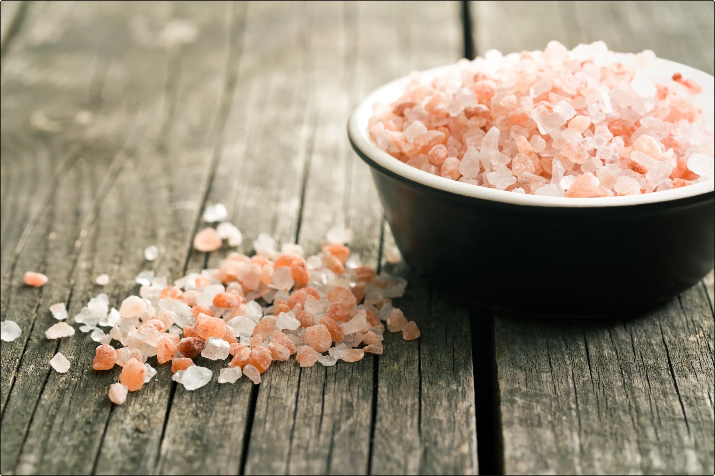 Pink himalayan rock salt in a bowl on wooden table