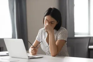 Woman with glasses working at computer and is tired