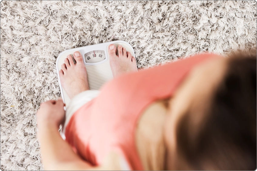 Overhead view of woman on weight scale at home, metabolism