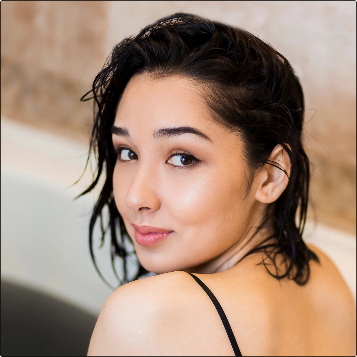beautiful woman sitting in bathtub wearing black lingerie looking back at camera