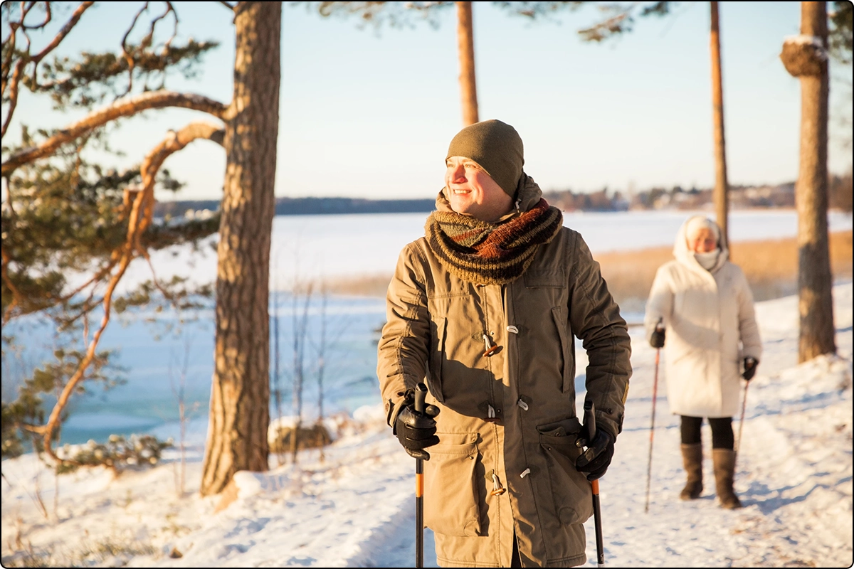 couple walking outdoors in winter with walking sticks enjoying getting vitamin d from sunlight