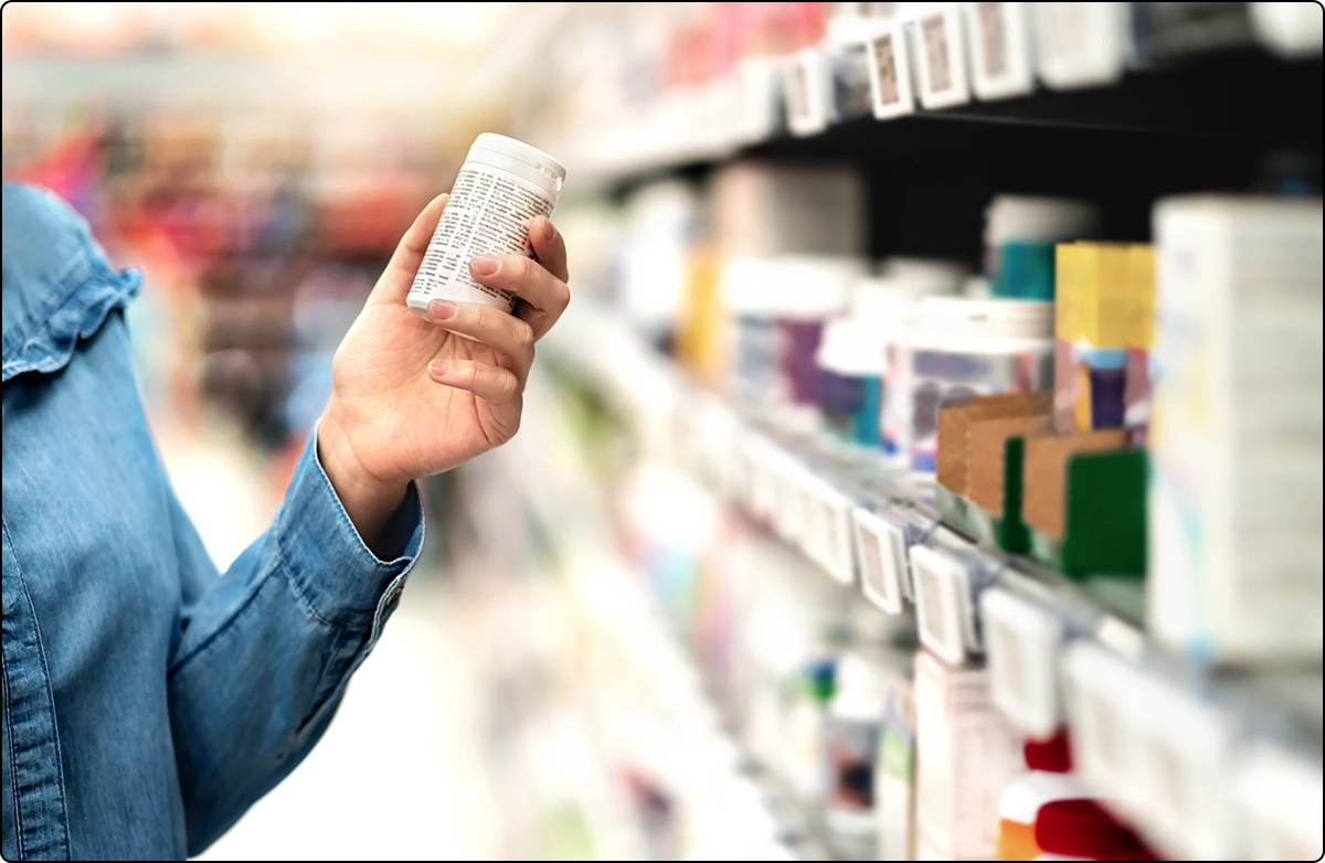 woman examining ingredients on multivitamins supplements bottle in store aisle