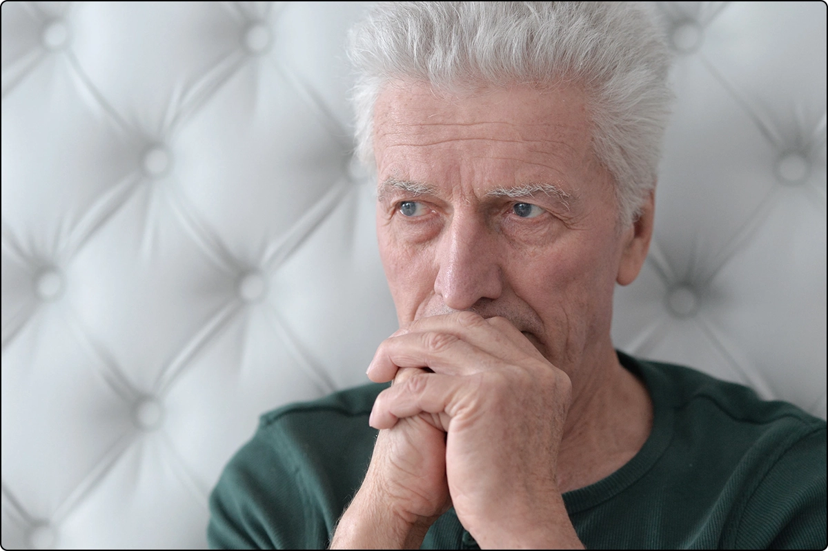 pensive senior man clasped hands in front of mouth