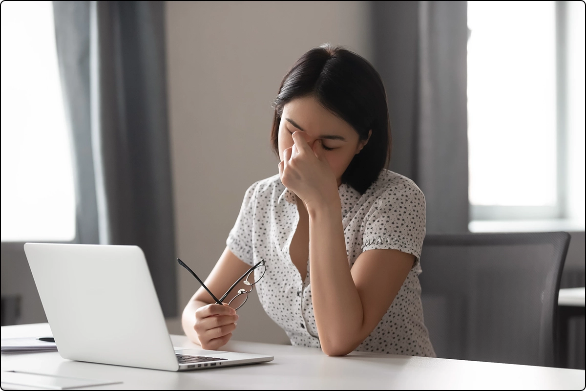 woman working at desk with laptop removed glasses rubbing tired eyes vitamin a deficiency